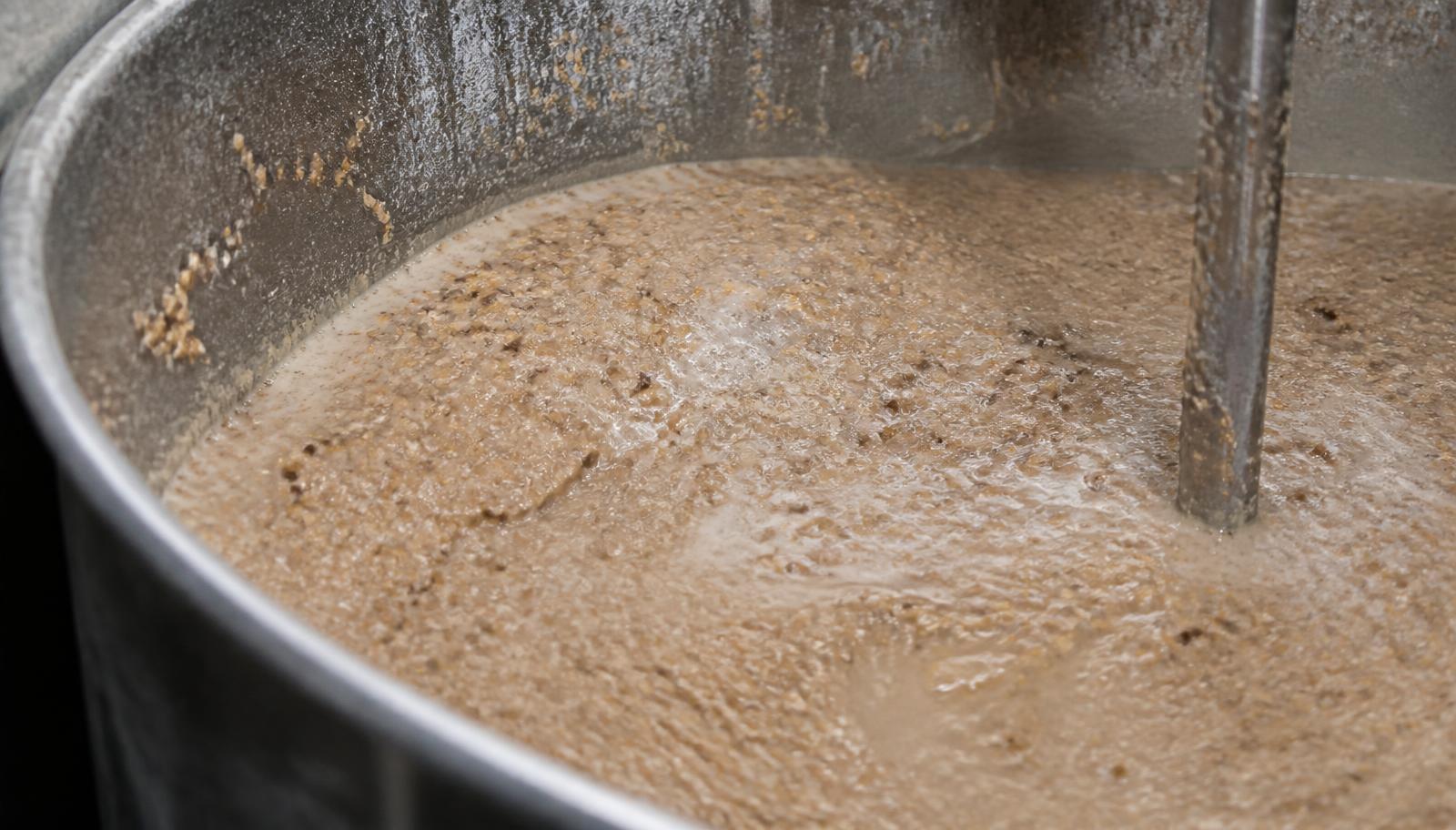 Cork granules being blended into a pale resin binder in an industrial mixing vessel